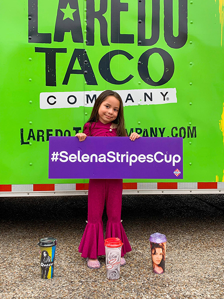 Young girl holding a #SelenaStripesCup sign